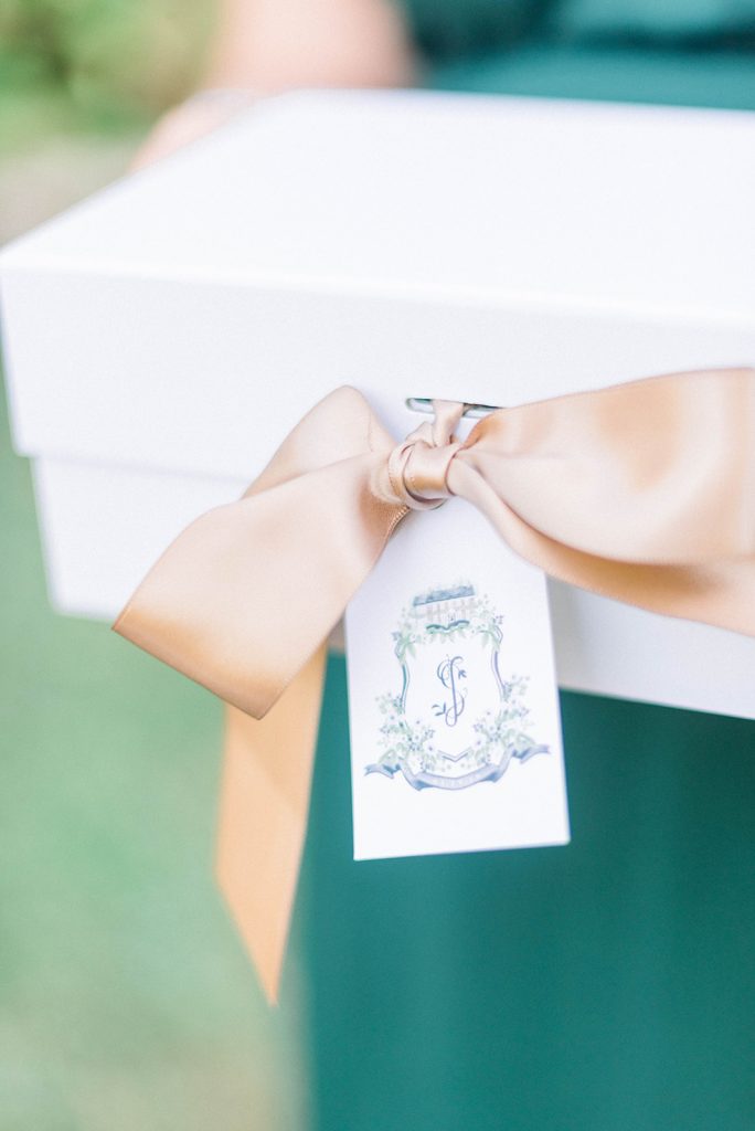 A gift box finished with satin ribbon and a watercolor crest gift tag by The Welcoming District.