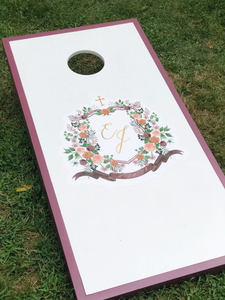 The couple's watercolor wedding crest was applied to a custom corn hole board offering a fun game and lots of personality to the wedding reception! The crest was painted by Alicia Betz of The Welcoming District.
